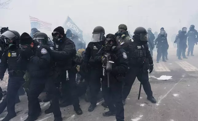 Federal immigration officers confront protesters outside Bishop Henry Whipple Federal Building, Thursday, Jan. 15, 2026, in Minneapolis. (AP Photo/Adam Gray)