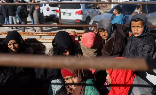 Displaced Syrians ride in the back of a truck near a humanitarian crossing declared by the Syrian army in the village of Hamima, in the eastern Aleppo countryside, near the front line with the Kurdish-led Syrian Democratic Forces in Deir Hafer, Syria, Thursday, Jan. 15, 2026. (AP Photo/Omar Albam)
