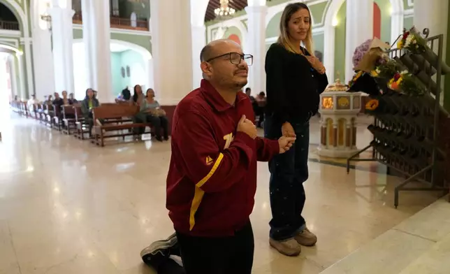 Carlos Rojas, a journalist freed after 18 months in jail, prays with his partner, Francy Fernandez, on the day of his release from prison at La Candelaria Church in Caracas, Venezuela, Wednesday, Jan. 14, 2026. (AP Photo/Ariana Cubillos)