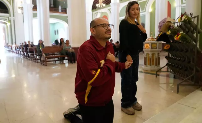 Carlos Rojas, a journalist freed after 18 months in jail, prays with his partner, Francy Fernandez, on the day of his release from prison at La Candelaria Church in Caracas, Venezuela, Wednesday, Jan. 14, 2026. (AP Photo/Ariana Cubillos)