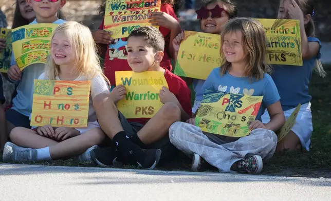 Students from an elementary school hold signs in support as wounded veterans ride past in the annual Florida Keys Soldier Ride organized by the Wounded Warrior Project, Friday, Jan. 9, 2026, in Islamorada, Fla. (AP Photo/Lynne Sladky)