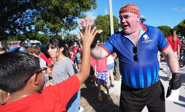U.S. Army and Marine veteran William Hansen high-five students as wounded veterans ride in the annual Florida Keys Soldier Ride organized by the Wounded Warrior Project, Friday, Jan. 9, 2026, in Islamorada, Fla. (AP Photo/Lynne Sladky)