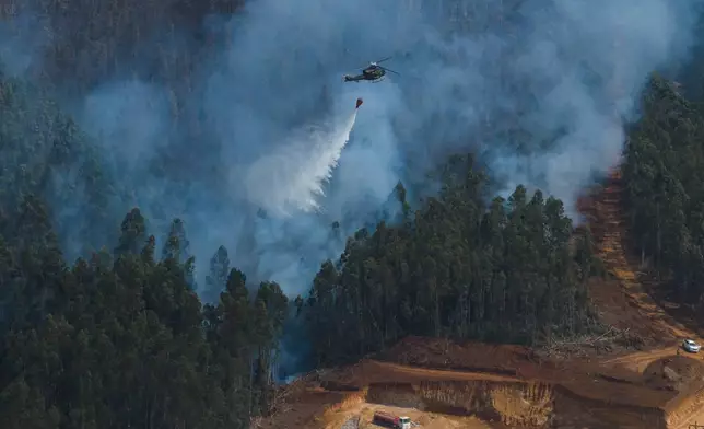 FILE - A helicopter drops water to battle wildfires near Concepcion, Chile, Jan. 19, 2026. (AP Photo/Javier Torres, File)
