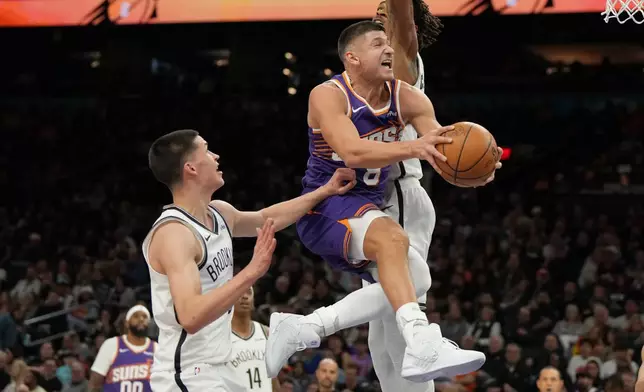 Phoenix Suns guard Grayson Allen (8) drives between Brooklyn Nets guard Egor Demin, left, and center Nic Claxton during the second half of an NBA basketball game, Tuesday, Jan. 27, 2026, in Phoenix. (AP Photo/Rick Scuteri)