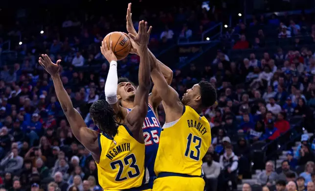 Philadelphia 76ers' Dom Barlow, center, goes up to shoot as he is fouled by Indiana Pacers' Tony Bradley, right, and defended by Aaron Nesmith, left, during the first half of an NBA basketball game, Monday, Jan. 19, 2026, in Philadelphia. (AP Photo/Chris Szagola)