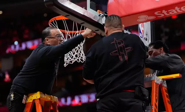 Crews replace a damaged hoop before an NBA basketball game between the San Antonio Spurs and the Houston Rockets in Houston, Tuesday, Jan. 20, 2026. (AP Photo/Ashley Landis)