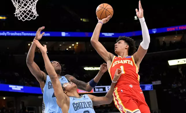 Atlanta Hawks forward Jalen Johnson (1) shoots against Memphis Grizzlies forwards Jaylen Wells (0) and GG Jackson II, left, in the first half of an NBA basketball game Wednesday, Jan. 21, 2026, in Memphis, Tenn. (AP Photo/Brandon Dill)