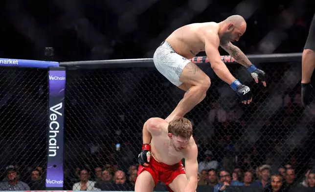 Jean Silva, top, jumps on the back of Arnold Allen, bottom, in a featherweight bout during the UFC 324 mixed martial arts event Saturday, Jan. 24, 2026, in Las Vegas. (AP Photo/Steve Marcus)