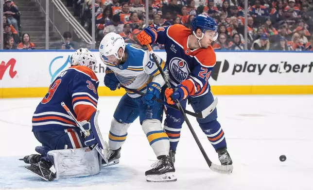 St. Louis Blues' Nathan Walker (26) and Edmonton Oilers' Spencer Stastney (24) battle on front as goalie Connor Ingram (39) makes the save during third period NHL hockey action, in Edmonton on Sunday, Jan. 18, 2026. (Jason Franson/The Canadian Press via AP)
