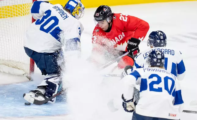 Canada's Sam O'Reilly, center, scores on Finland goaltender Petteri Rimpinen (30) while teammates Kasper Pikkarainen (20) and Max Westergard, second from right, defend during the first period of an IIHF World Junior Hockey Championship bronze medal game in St. Paul, Minn., Monday, Jan. 5, 2026. (Christopher Katsarov/The Canadian Press via AP)