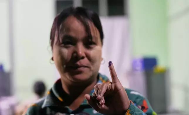 A voter holds up her finger marked with ink indicating she voted at a polling station during the third phase of general election in Mandalay, central Myanmar, Sunday, Jan. 25, 2026. (AP Photo/Aung Shine Oo)