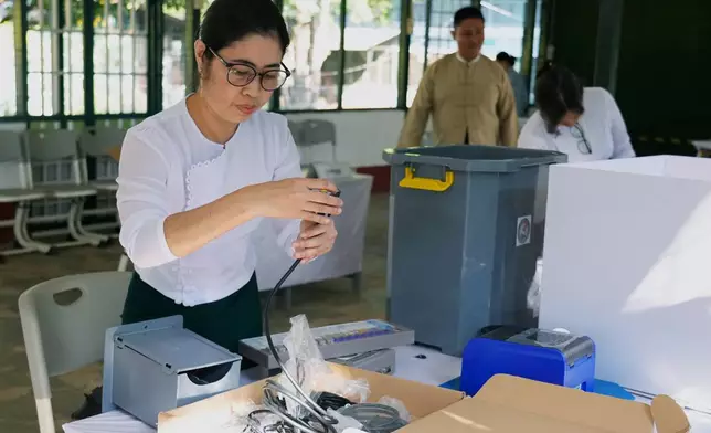 An official of the Union Election Commission sets up an electronic voting machine at a polling station, one day ahead of the third phase of the general election, in Yangon, Myanmar, Saturday, Jan. 24, 2026. (AP Photo/Thein Zaw)