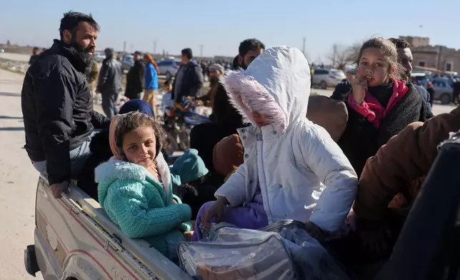 Displaced Syrian children and women ride in the back of a truck near a humanitarian crossing declared by the Syrian army in the village of Hamima, in the eastern Aleppo countryside, near the front line with the Kurdish-led Syrian Democratic Forces in Deir Hafer, Syria, Thursday, Jan. 15, 2026. (AP Photo/Omar Albam)