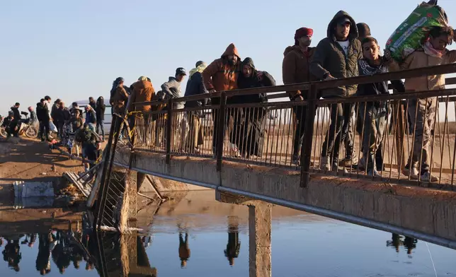 Displaced Syrians at a river crossing near the village of Jarirat al Imam, in the eastern Aleppo countryside, near the front line with the Kurdish-led Syrian Democratic Forces in Deir Hafer, Syria, Thursday, Jan. 15, 2026. (AP Photo/Omar Albam)