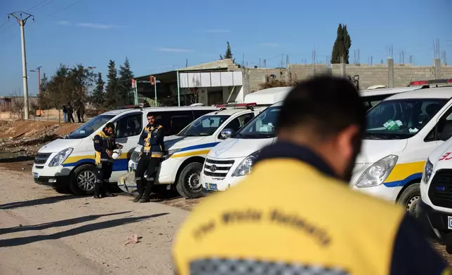 Members of the Syrian Civil Defense, stand next to their vehicles at a humanitarian crossing declared by the Syrian army in the village of Hamima, in the eastern Aleppo countryside, near the front line with the Kurdish-led Syrian Democratic Forces in Deir Hafer, Syria, Thursday, Jan. 15, 2026. (AP Photo/Ghaith Alsayed)