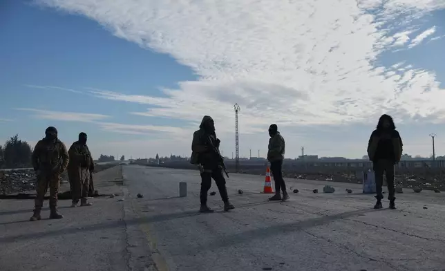 Members of the Syrian military police stand at a humanitarian crossing declared by the Syrian army in the village of Hamima, in the eastern Aleppo countryside, near the front line with the Kurdish-led Syrian Democratic Forces in Deir Hafer, Syria, Thursday, Jan. 15, 2026. (AP Photo/Ghaith Alsayed)