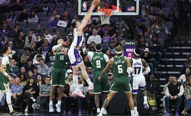 Sacramento Kings center Drew Eubanks, center, makes an alley-oop dunk surrounded by Milwaukee Bucks defenders during the first half of an NBA basketball game, Sunday, Jan. 4, 2026, in Sacramento, Calif. (AP Photo/Sara Nevis)