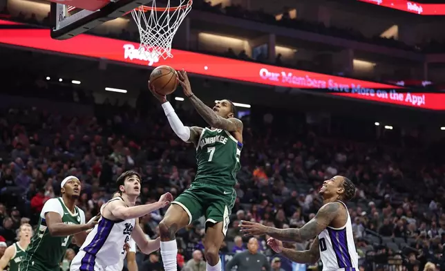 Milwaukee Bucks guard Kevin Porter Jr. (7) goes up for a layup with Sacramento Kings center Maxime Raynaud, second from left, and guard Demar Derozan, right, defending during the first half of an NBA basketball game, Sunday, Jan. 4, 2026, in Sacramento, Calif. (AP Photo/Sara Nevis)