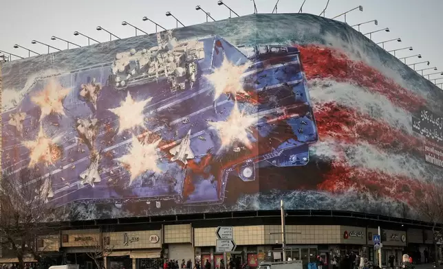 A billboard depicting a damaged U.S. aircraft carrier with disabled fighter jets on its deck and a sign reading in Farsi and English, "If you sow the wind, you'll reap the whirlwind," is seen at Enqelab-e-Eslami (Islamic Revolution) Square in Tehran, Iran, Sunday, Jan. 25, 2026. (AP Photo/Vahid Salemi)