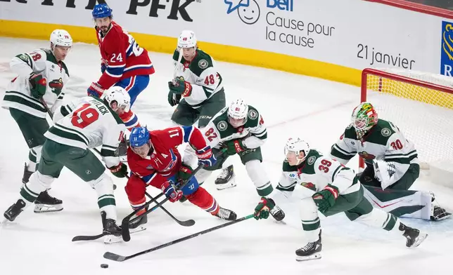Montreal Canadiens' Brendan Gallagher (11) battles for the puck between Minnesota Wild's Tyler Pitlick (19), David Spacek (82) and Ben Jones (39 during the second period of an NHL hockey game in Montreal, Tuesday, Jan. 20, 2026. (Christinne Muschi/The Canadian Press via AP)