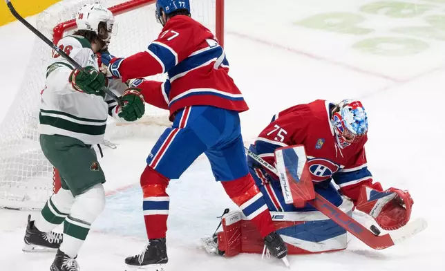 Montreal Canadiens goaltender Jakub Dobes (75) makes a save as Minnesota Wild's Ryan Hartman (38) and Canadiens' Kirby Dach (77) battle for the rebound during the second period of an NHL hockey game in Montreal, Tuesday, Jan. 20, 2026. (Christinne Muschi/The Canadian Press via AP)