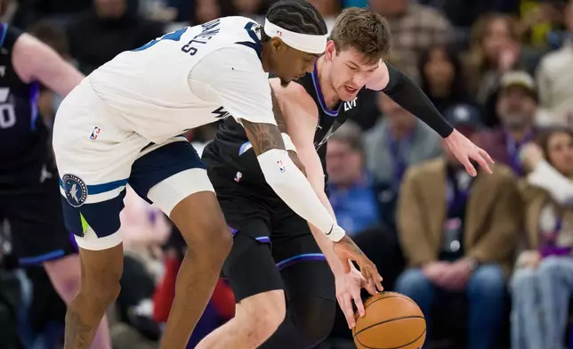 Minnesota Timberwolves forward Jaden McDaniels, left, and Utah Jazz center Kyle Filipowski, behind, fight for the ball during the first half of an NBA basketball game Tuesday, Jan. 20, 2026, in Salt Lake City. (AP Photo/Bethany Baker)
