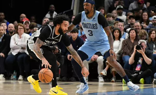 San Antonio Spurs forward Julian Champagnie (30) handles the ball against Memphis Grizzlies guard Kentavious Caldwell-Pope (3) in the first half of an NBA basketball game Tuesday, Jan. 6, 2026, in Memphis, Tenn. (AP Photo/Brandon Dill)