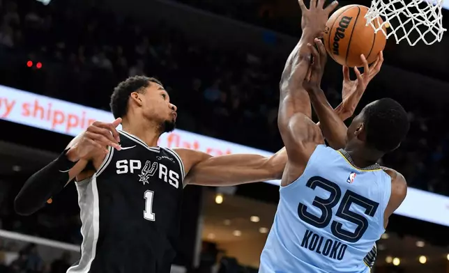 San Antonio Spurs forward Victor Wembanyama (1) and Memphis Grizzlies center Christian Koloko (35) reach for the ball in the first half of an NBA basketball game Tuesday, Jan. 6, 2026, in Memphis, Tenn. (AP Photo/Brandon Dill)