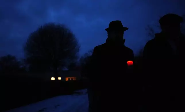 A man walks with a candle during the International Holocaust Remembrance Day at the former Nazi concentration camp in Terezin, Czech Republic, Tuesday, Jan. 27, 2026. (AP Photo/Petr David Josek)