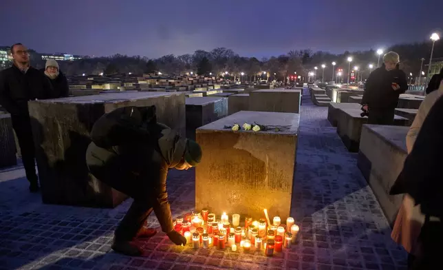 People light candles during a vigil at the Holocaust memorial on the eve of the International Holocaust Memorial Day in Berlin, Germany, Monday, Jan. 26, 2026. (AP Photo/Markus Schreiber)