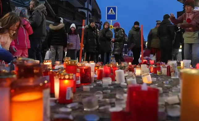 People light candles near the sealed off Le Constellation bar in Crans-Montana, Swiss Alps, Switzerland, Friday, Jan. 2, 2026, where a devastating fire left dead and injured during the New Year's celebrations. (AP Photo/ Antonio Calanni)