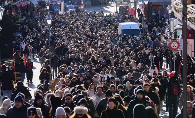 People walk during a memorial procession in Crans-Montana, Swiss Alps, Switzerland, Sunday, Jan. 4, 2026, after a devastating fire in Le Constellation bar left dead and injured during the New Year's celebrations. (AP Photo/ Antonio Calanni)