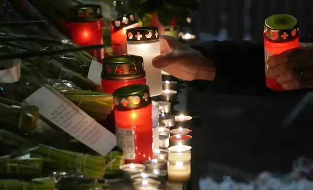 People lay candles and flowers near the Le Constellation bar, where a devastating fire left dead and injured during the New Year's celebrations in Crans-Montana, Swiss Alps, Switzerland, Thursday, Jan. 1, 2026. (AP Photo/ Antonio Calanni)