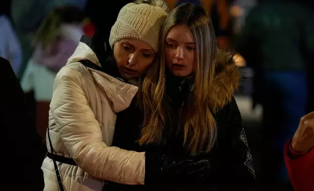 People mourn near the sealed off Le Constellation bar in Crans-Montana, Swiss Alps, Switzerland, Friday, Jan. 2, 2026, where a devastating fire left dead and injured during the New Year's celebrations. (AP Photo/Baz Ratner)