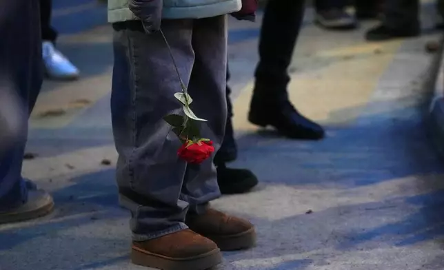 People bring flowers near the sealed off Le Constellation bar in Crans-Montana, Swiss Alps, Switzerland, Friday, Jan. 2, 2026, where a devastating fire left dead and injured during the New Year's celebrations. (AP Photo/ Antonio Calanni)
