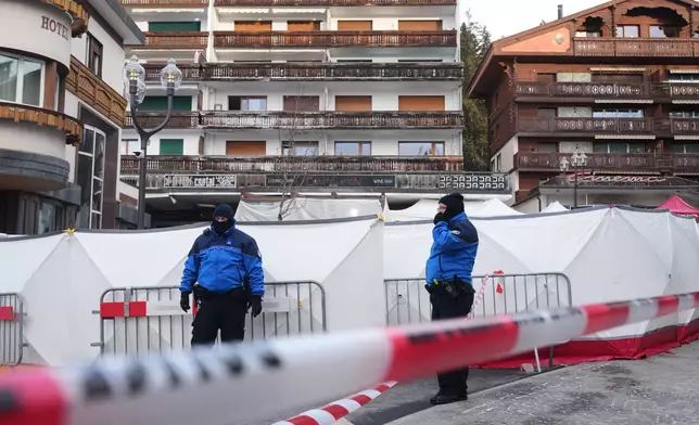 Security stands in front of the sealed off Le Constellation bar, where a devastating fire left dead and injured during the New Year's celebrations in Crans-Montana, Swiss Alps, Switzerland, Friday morning, Jan. 2, 2026. (AP Photo/ Antonio Calanni)