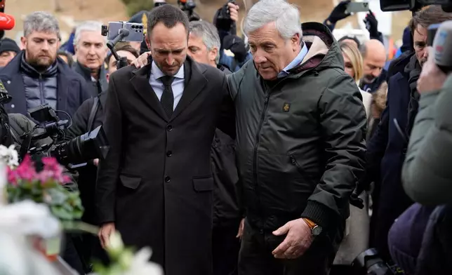 Italian Foreign Minister Antonio Tajani, right, and Valais regional government Mathias Reynard pay tribute at the sealed off Le Constellation bar, where a devastating fire left dead and injured during the New Year's celebrations in Crans-Montana, Swiss Alps, Switzerland, Friday, Jan. 2, 2026. (AP Photo/Baz Ratner)
