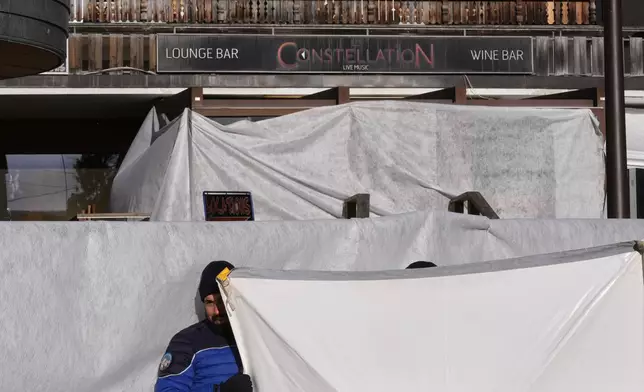 Security stands in front of the sealed off Le Constellation bar, where a devastating fire left dead and injured during the New Year's celebrations in Crans-Montana, Swiss Alps, Switzerland, Friday morning, Jan. 2, 2026. (AP Photo/ Antonio Calanni)