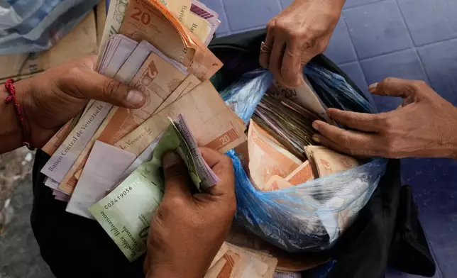People exchange U.S. dollars for Venezuelan bolivars at a street market in Caracas, Venezuela, Thursday, Jan. 8, 2026. (AP Photo/Matias Delacroix)