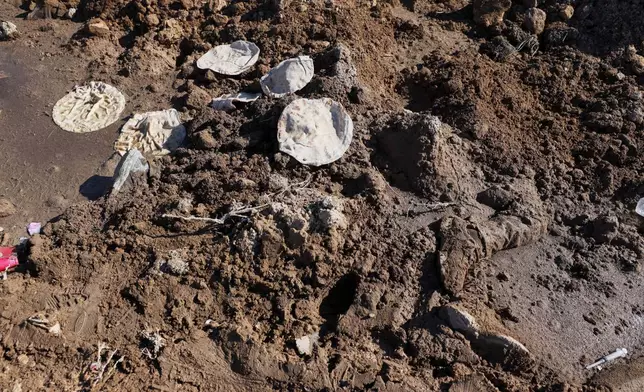 A body lies covered by dirt on the side of the road between government-controlled Raqqa and SDF-controlled Hassakeh in northeastern Syria, Tuesday Jan. 20, 2026. (AP Photo/Omar Albam)
