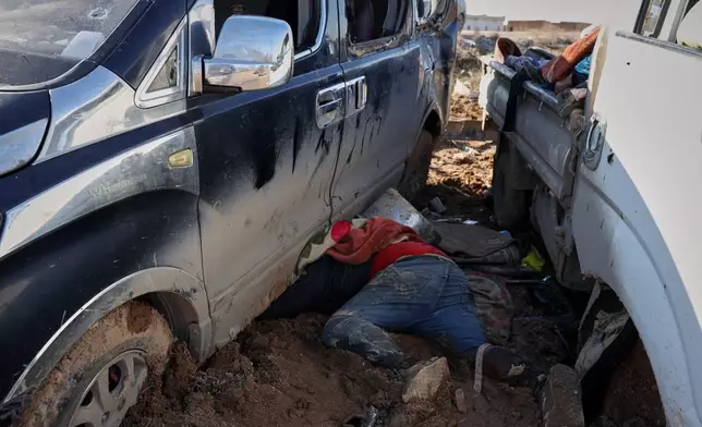 The body of a civilian lies in between two trucks along a road between government-controlled Raqqa and SDF-controlled Hassakeh in northeastern Syria, Tuesday, Jan. 20, 2026. (AP Photo/Omar Albam)