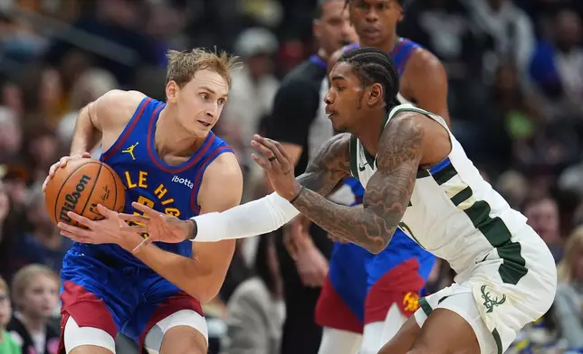 Milwaukee Bucks guard Kevin Porter Jr., right, tries to steal the ball form Denver Nuggets forward Hunter Tyson in the first half of an NBA basketball game, Sunday, Jan. 11, 2026, in Denver. (AP Photo/David Zalubowski)