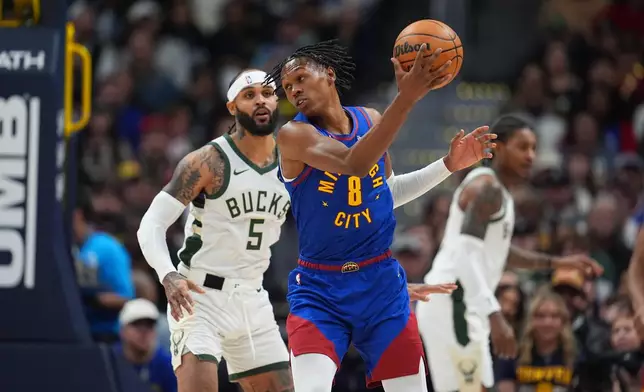 Denver Nuggets guard Peyton Watson, front, fields a pass as Milwaukee Bucks guard Gary Trent Jr. defends in the first half of an NBA basketball game, Sunday, Jan. 11, 2026, in Denver. (AP Photo/David Zalubowski)