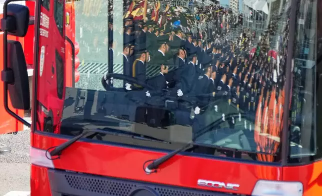 Members of fire brigades are reflected on a front window of the latest fire engine during the annual New Year's Fire Brigade Review Tuesday, Jan. 6, 2026, in Tokyo. (AP Photo/Eugene Hoshiko)