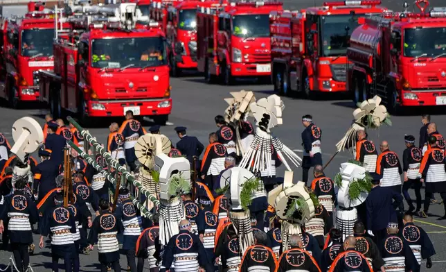 Members of a traditional firefighting preservation group retreat from the venue near latest fire engines during the annual New Year's Fire Brigade Review Tuesday, Jan. 6, 2026, in Tokyo. (AP Photo/Eugene Hoshiko)