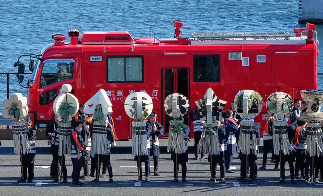 Members of a traditional firefighting preservation group hold a matoi, a traditional flag once used by Edo-period fire brigades as a the latest fire engine past by during the annual New Year's Fire Brigade Review Tuesday, Jan. 6, 2026, in Tokyo. (AP Photo/Eugene Hoshiko)