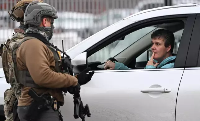 Federal agents talk with a person inside a vehicle outside the Bishop Henry Whipple Federal Building, Thursday, Jan. 8, 2026, in Minneapolis, Minn. (AP Photo/Tom Baker)