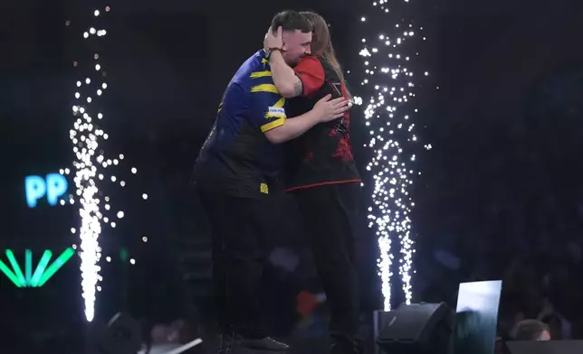 England's Luke Littler, left, reacts after winning the World Darts Championships semifinal match against England's Ryan Searle at Alexandra Palace in London, Friday, Jan. 2, 2026.(AP Photo/Dave Shopland)