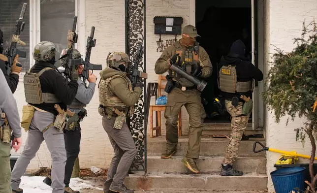 Federal immigration officers prepare to enter a home to make an arrest after an officer used a battering ram to break down a door Sunday, Jan. 11, 2026, in Minneapolis. (AP Photo/John Locher)