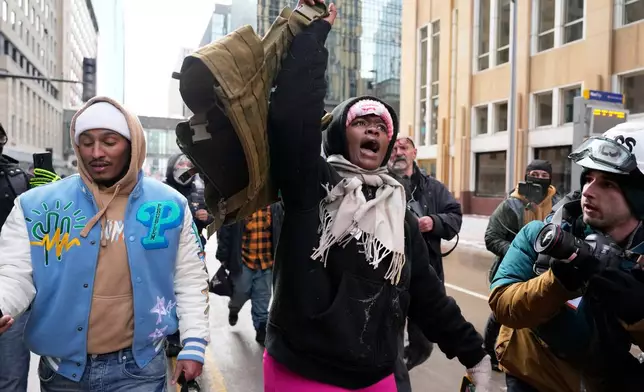 A pro-immigration protester lifts up Jake Lang's vest after an altercation at the March Against Minnesota Fraud rally near Minneapolis City Hall, Saturday, Jan. 17, 2026, in Minneapolis. (AP Photo/Yuki Iwamura)